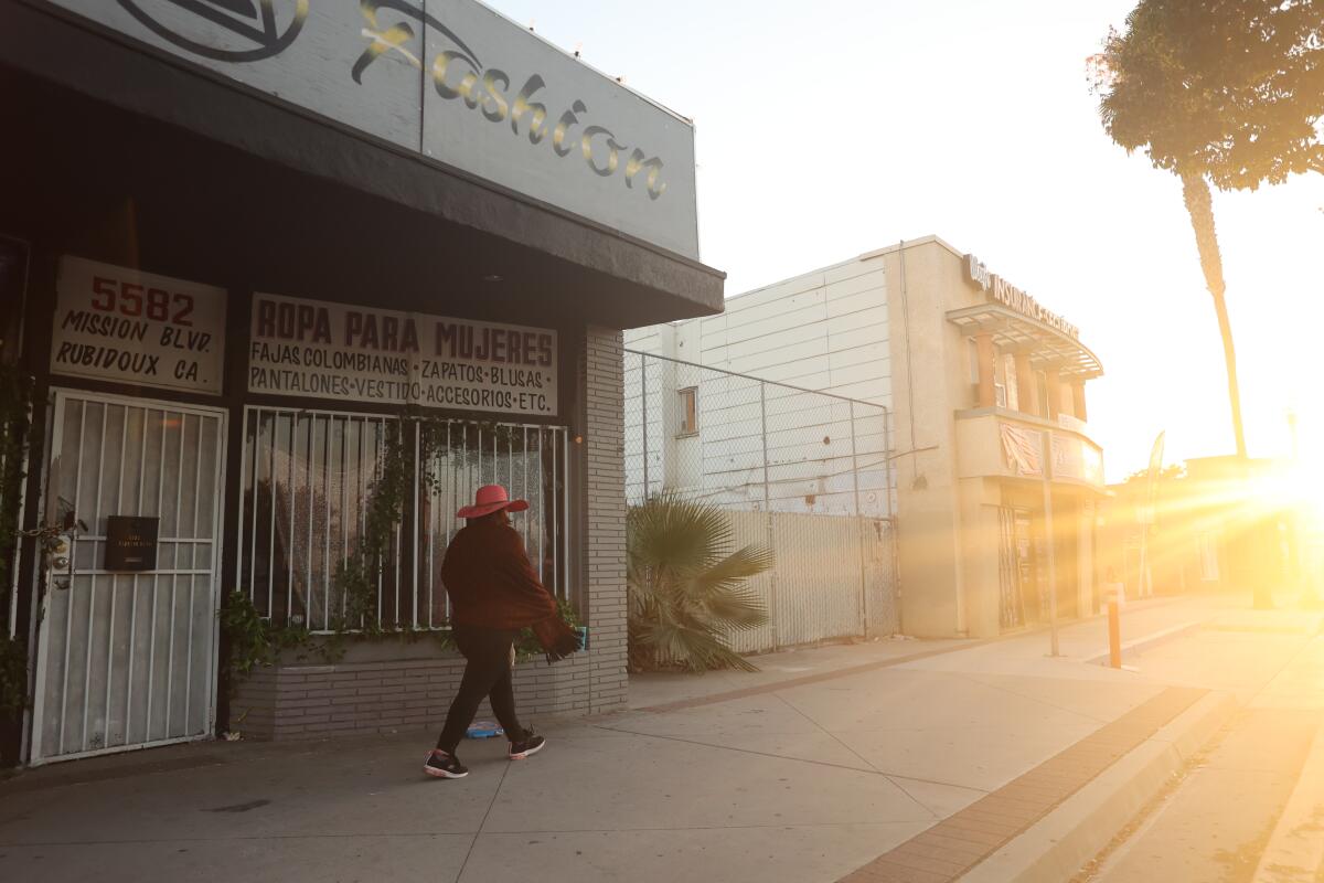 A person walking past Rubidoux Fashion at sunset