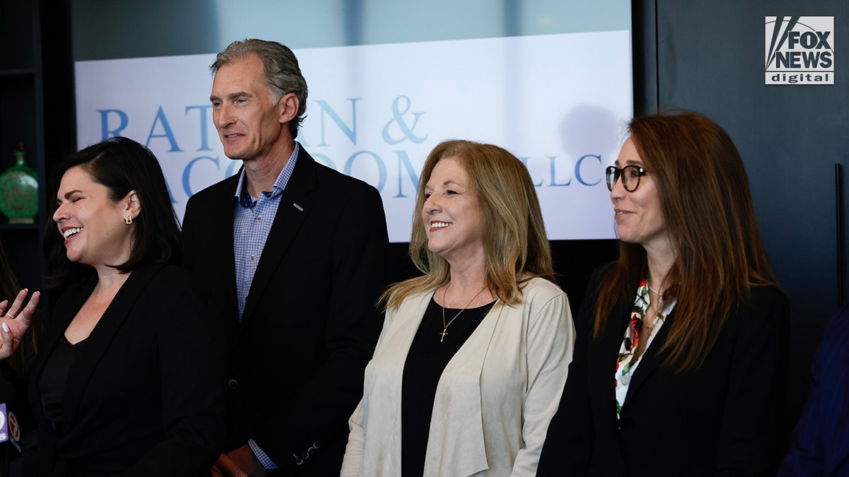 Deborah Clenney and Kim Clenney smile as their attorney Jude Faccidomo speaks to the press