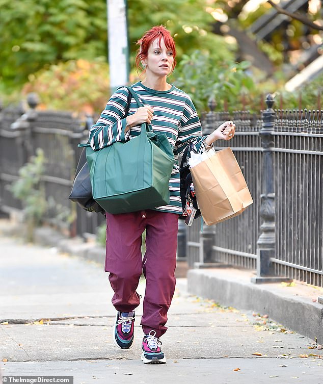 Lily Allen, 39, was spotted grocery shopping in New York City on Monday wearing a quirky outfit which included a pair of maroon trousers and an oversized green and white T-shirt