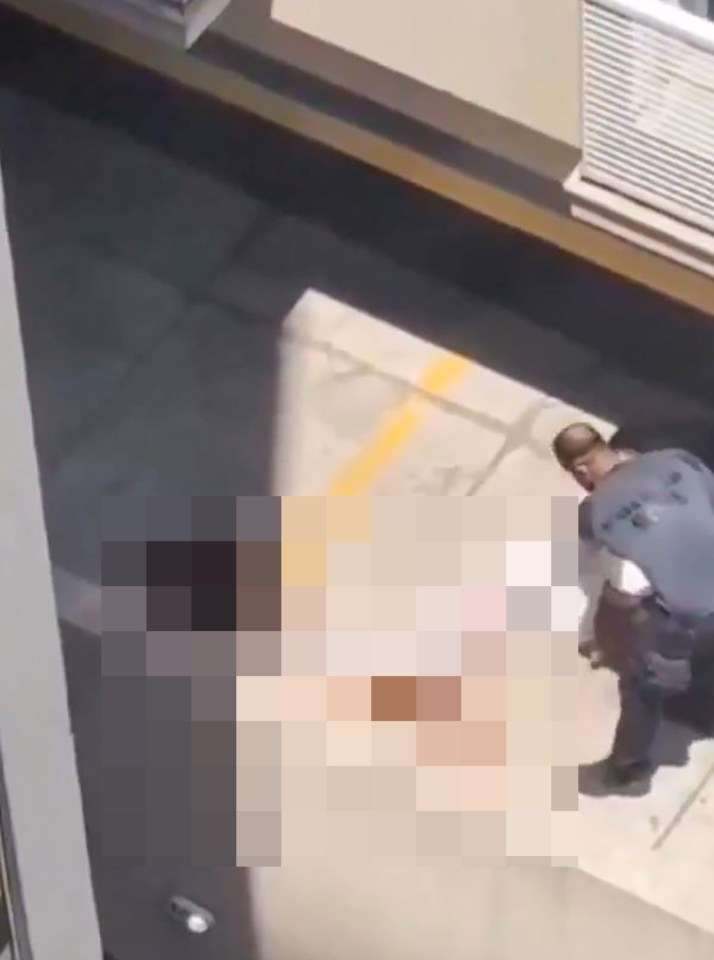 Video still showing a person lying on the ground while another person attends to them.