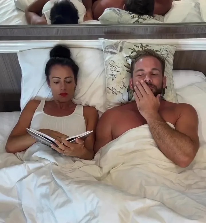 Couple in bed; one is reading.