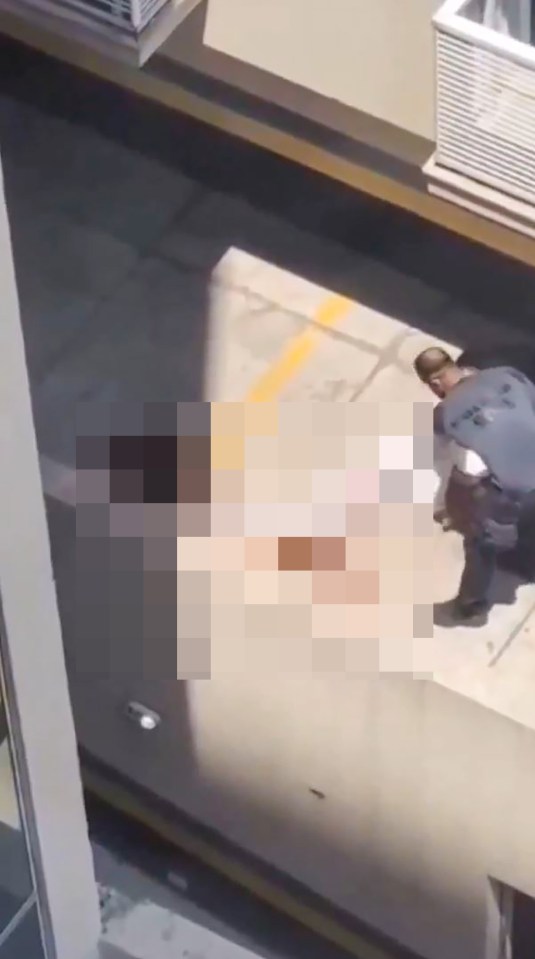 Video still showing a person lying on the ground while another person attends to them.