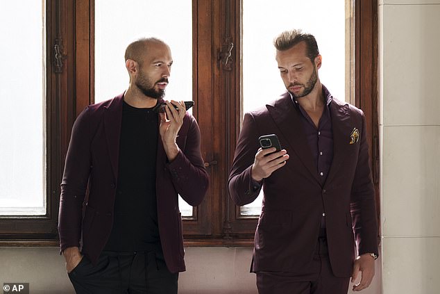 Andrew Tate, left, and his brother Tristan, right, wait at the Court of Appeals building in Bucharest, Romania, Tuesday, Oct. 15, 2024. The Tate brothers have been fighting civil and criminal cases in Romania and Britain