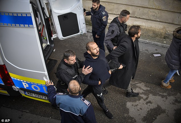 Police officers escort Andrew Tate, third from left, handcuffed to his brother Tristan, to the Court of Appeal in Bucharest, Romania on Feb. 1, 2023