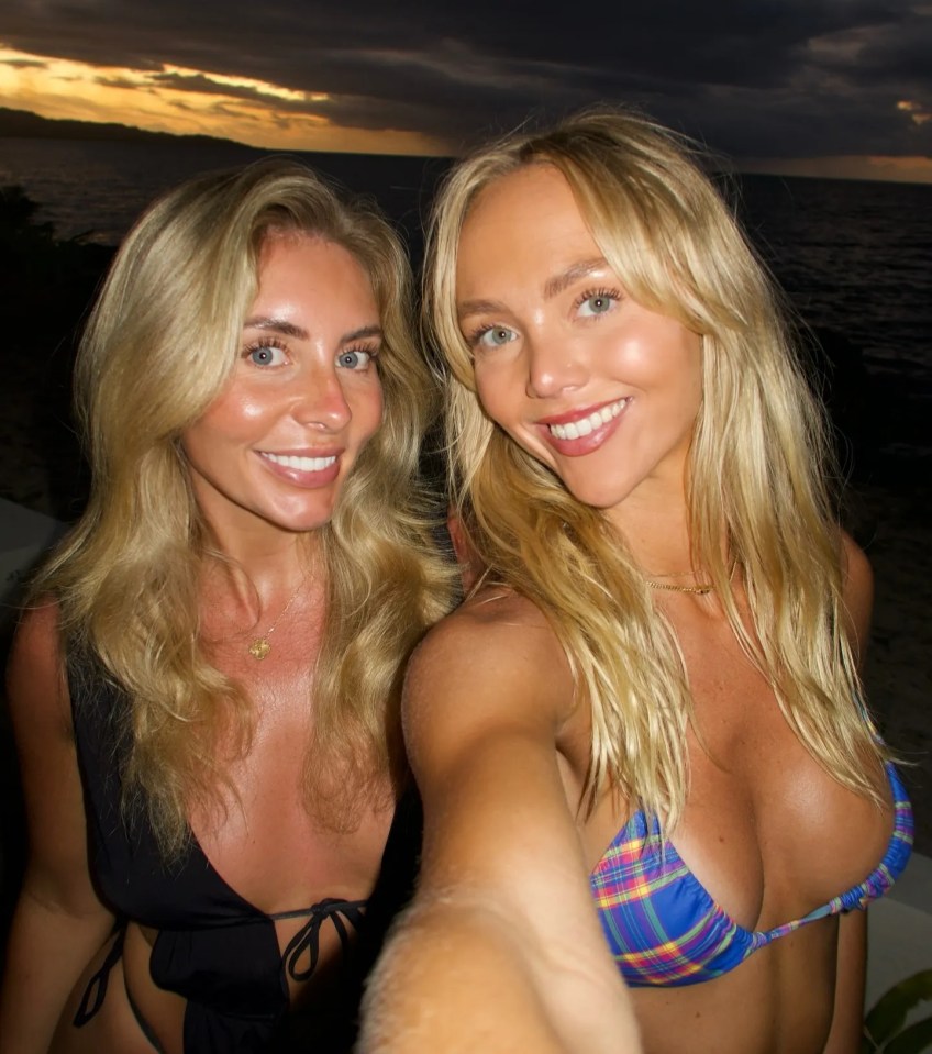 Selfie of two blonde women in bikinis at sunset.