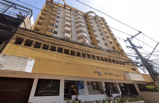 Low-angle view of a multi-story building with shops on the ground floor.