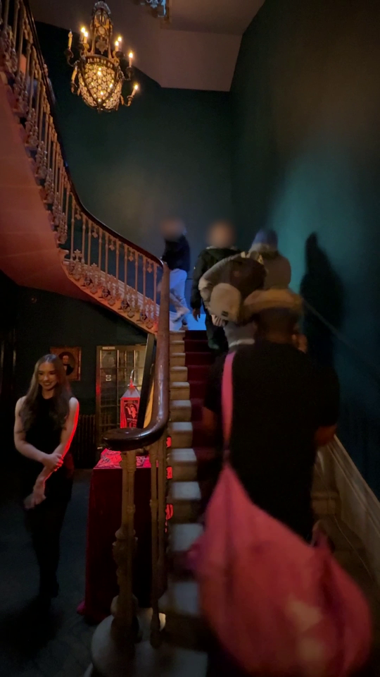 People ascending a grand staircase in a dark building.