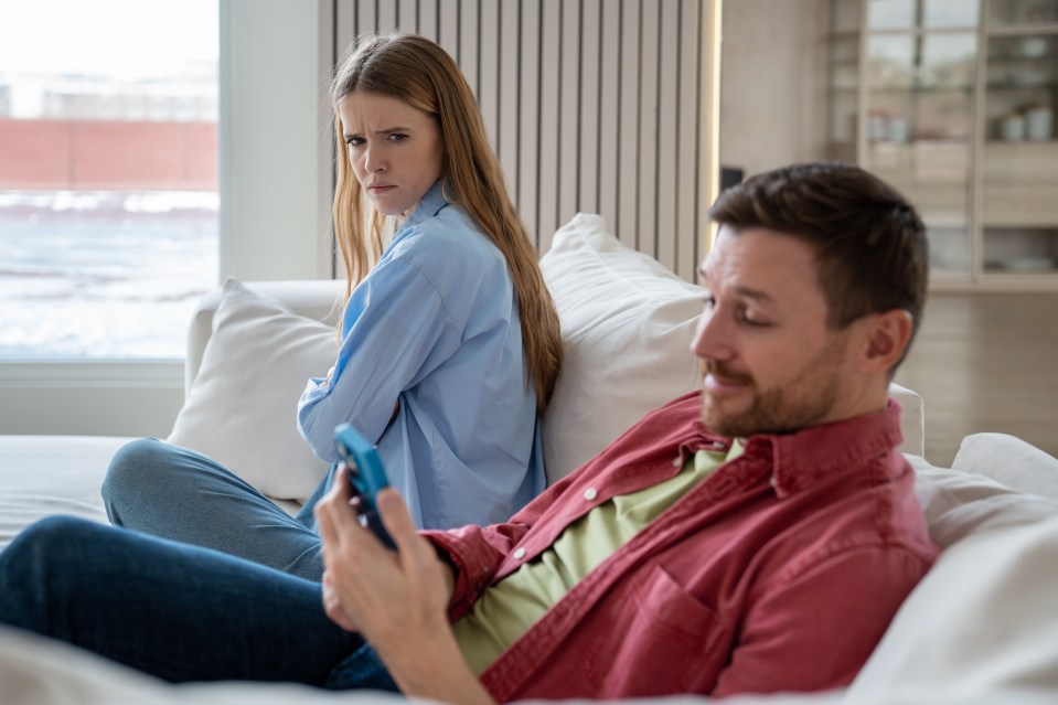 Angry woman ignoring man on his phone.