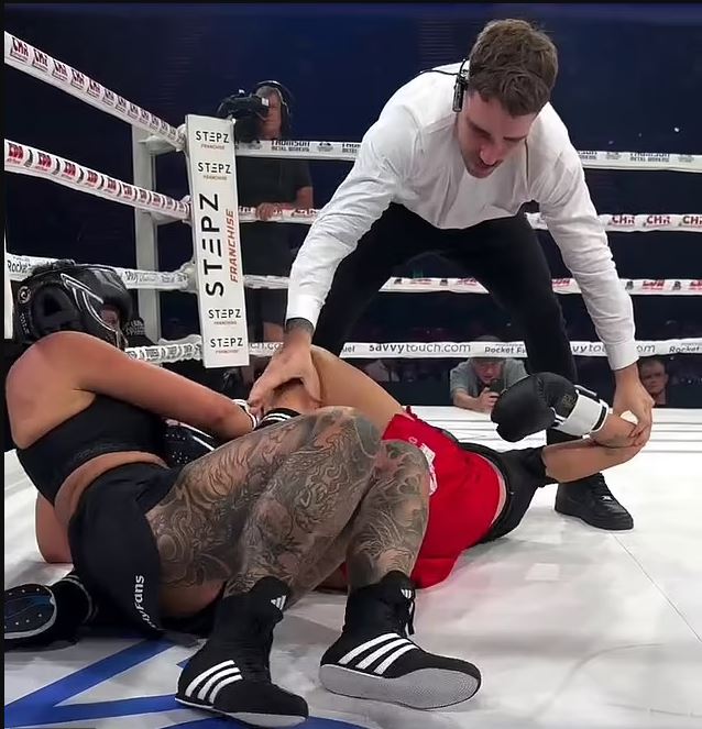Referee assisting a boxer after a match.