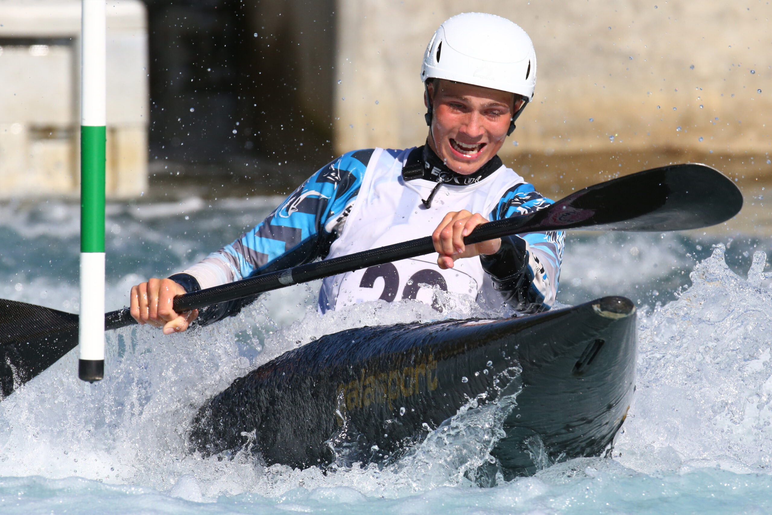 A man kayaking in a canoe slalom competition.