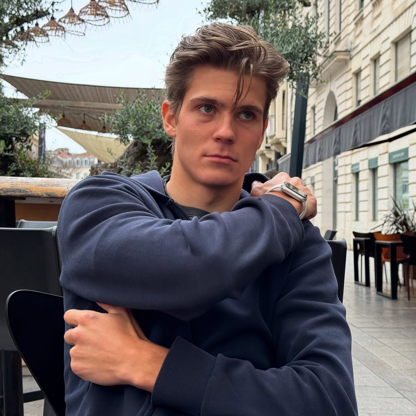 Young man sitting outdoors wearing a navy blue hoodie.